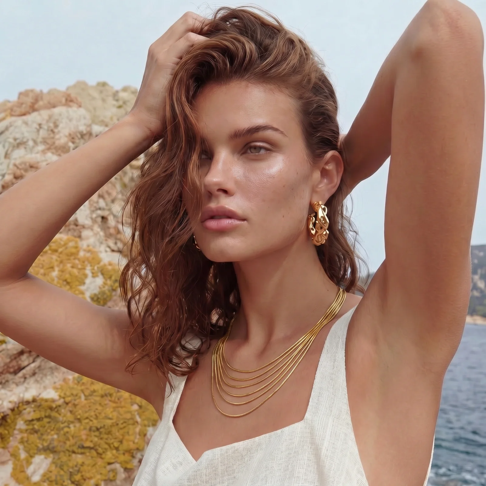 Model wearing multi-strand gold chain necklace by the sea
